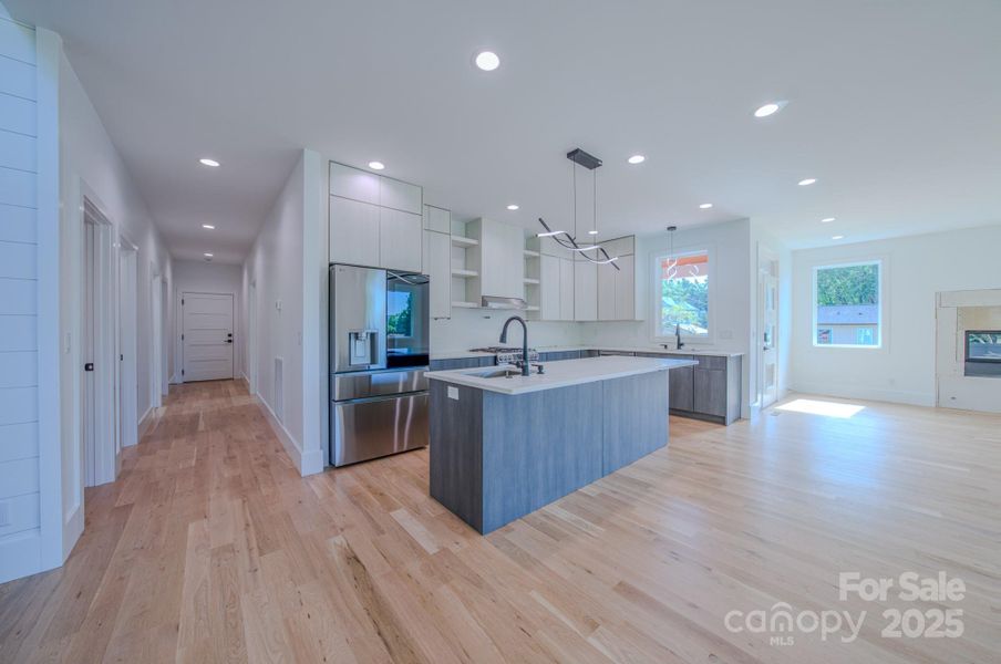 Kitchen view and hallway leading towards garage, suite, laundry/pantry and half bath.