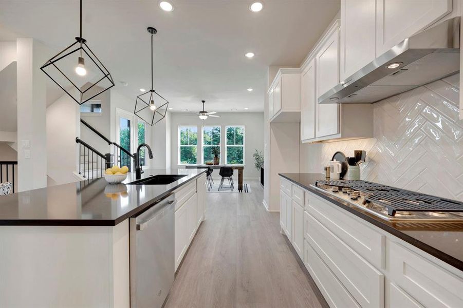 Modern kitchen featuring white shaker cabinetry, dark countertops, a stainless steel dishwasher, and a black sink with a gooseneck faucet
