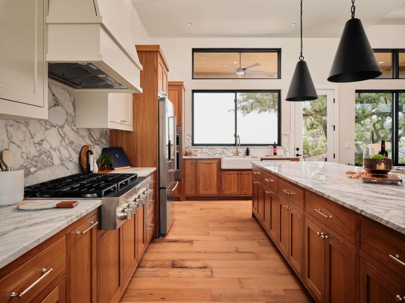 An inviting kitchen with rich wood cabinetry, marble counters, and an abundance of natural light. An inviting kitchen with rich wood cabinetry, marble counters, and an abundance of natural light.
