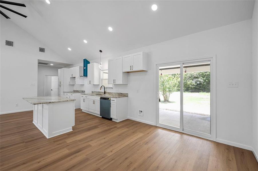 Open-concept living space featuring a vaulted ceiling, wood-finish flooring, and recessed lighting Open-concept living space featuring a vaulted ceiling, wood-finish flooring, and recessed lighting