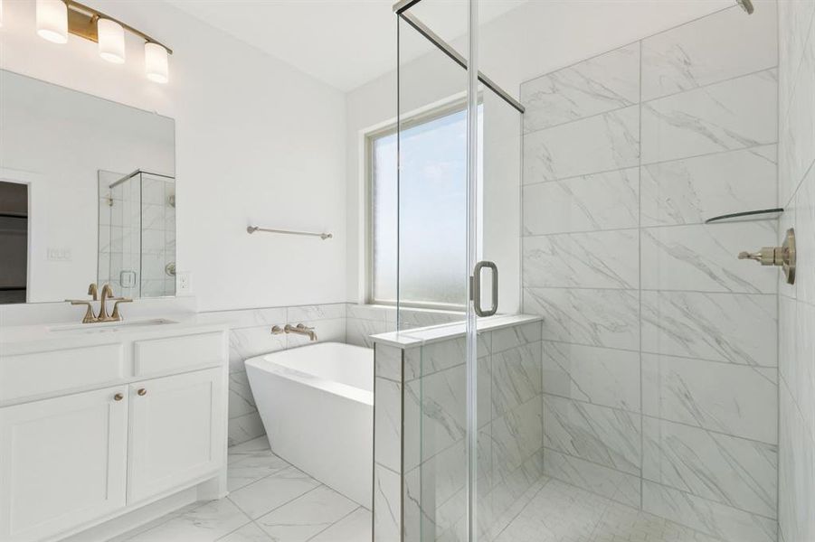 Full bathroom with vanity, a soaking tub, a stall shower, light marble finish flooring, and tile walls