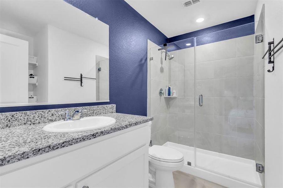 Full bath with a shower stall, vanity, and a textured wall