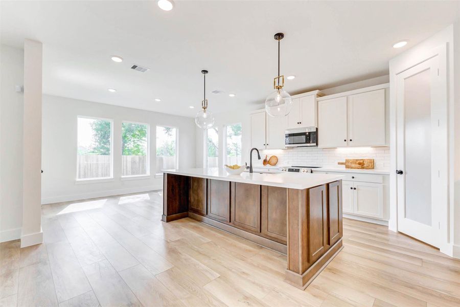 A chef’s dream kitchen!Open-concept layout with a large island in a walnut color stain, walk-in pantry behind an elegant frosted glass 8ft door, and premium quartz countertops. A chef’s dream kitchen!Open-concept layout with a large island in a walnut color stain, walk-in pantry behind an elegant frosted glass 8ft door, and premium quartz countertops.