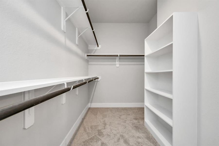 Step into a walk-in closet that defines luxury and functionality. This generously sized space boasts built-in shelving, providing ample room for organization. Sample photo of completed home with similar plan. As built color and selections will vary.