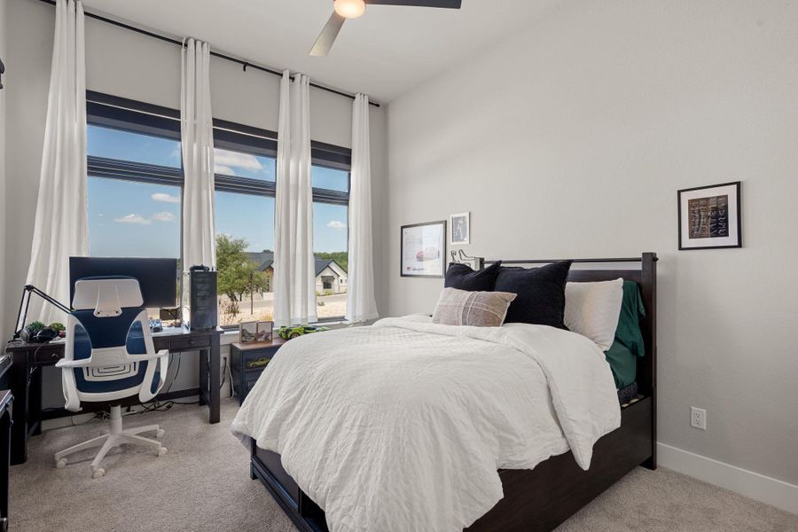 High ceilings and tall windows frame expansive neighborhood views in this peaceful bedroom.