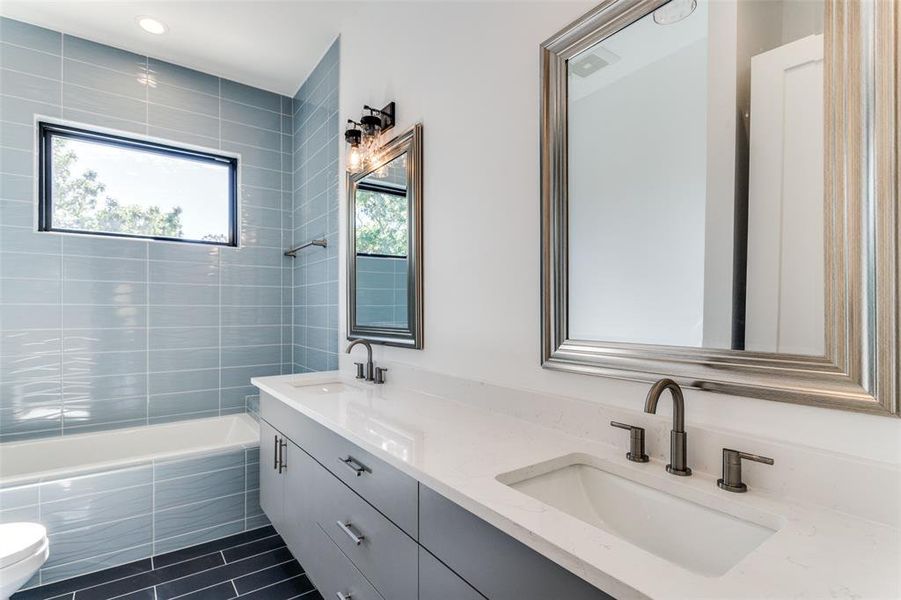 Full bathroom with vanity, tiled shower / bath combo, toilet, and tile patterned floors