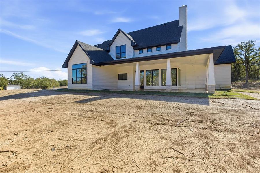 View of front of property featuring a patio, roof with shingles, and a chimney View of front of property featuring a patio, roof with shingles, and a chimney