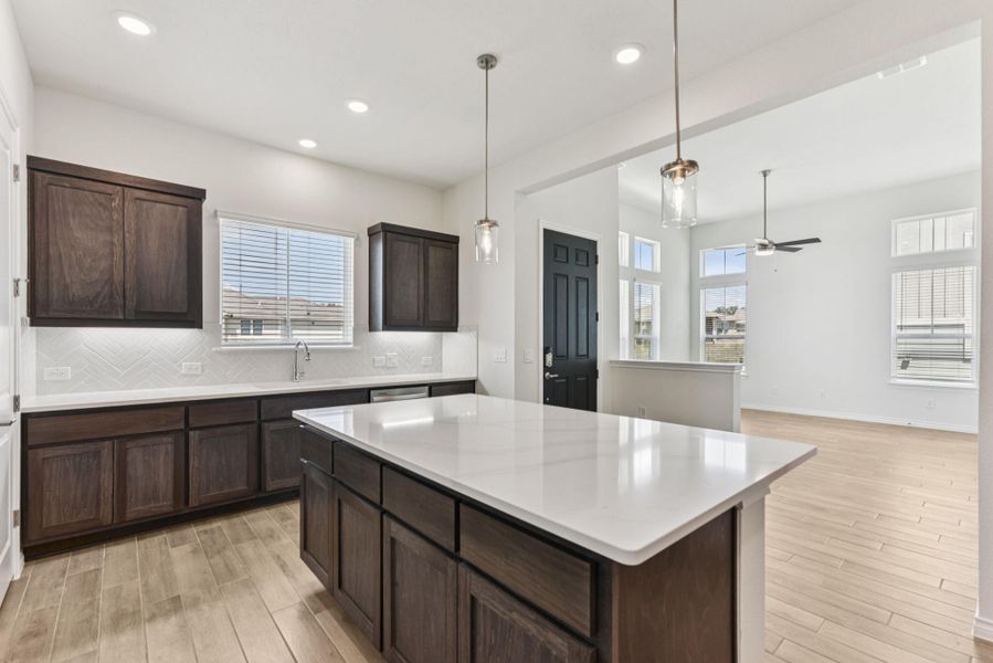 Kitchen with dark brown cabinets, decorative backsplash, a kitchen island, plenty of natural light, and recessed lighting Kitchen with dark brown cabinets, decorative backsplash, a kitchen island, plenty of natural light, and recessed lighting