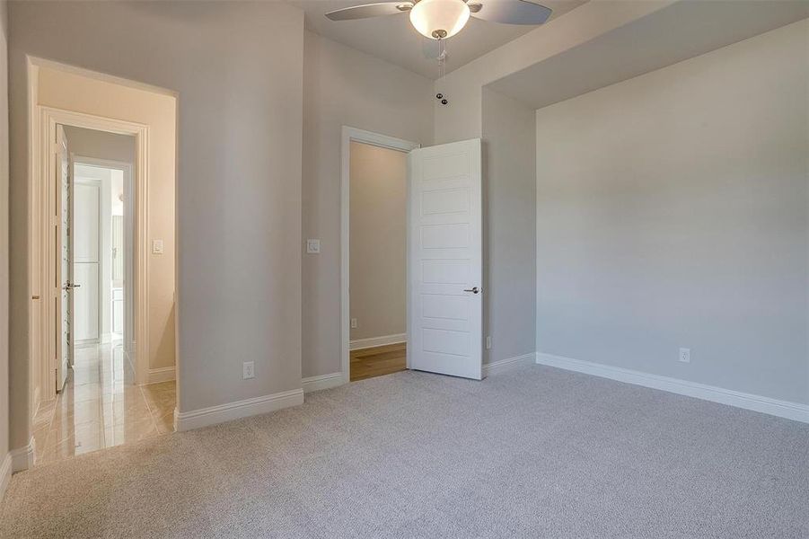 Unfurnished bedroom with light colored carpet and ceiling fan