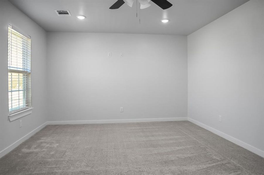 Spare room featuring carpet, a healthy amount of sunlight, and ceiling fan