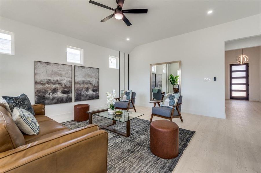 Living room featuring baseboards, lofted ceiling, ceiling fan, light wood-type flooring, and recessed lighting
