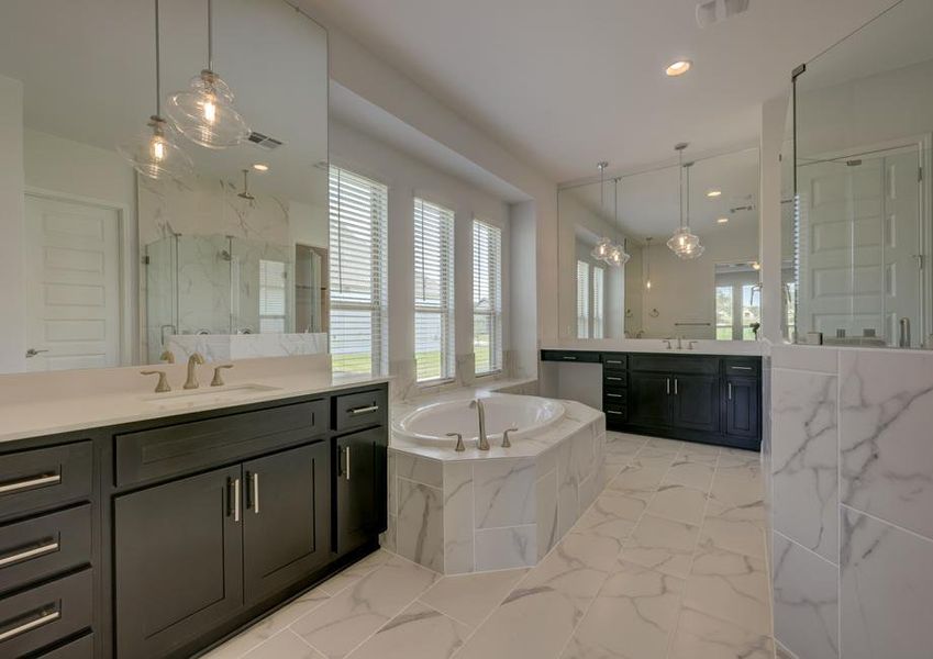 Stunning, spa-like master bath that features two vanity areas, a soaking tub, and walk-in shower.