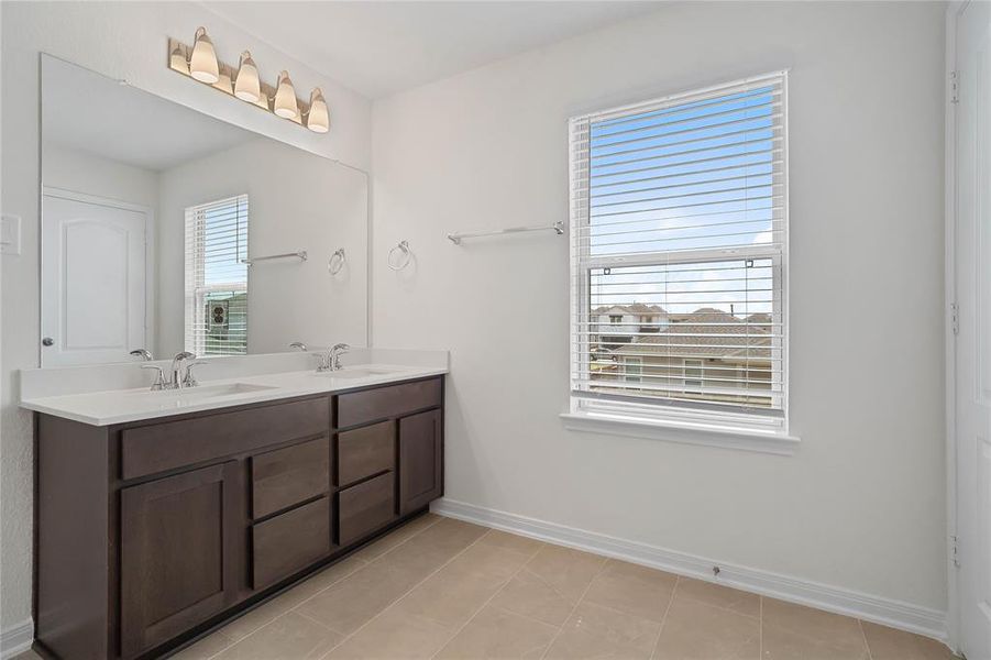 This primary bathroom is definitely move-in ready! Featuring an oversized tub and shower combination with tile surround, stained cabinets with light countertops, high ceilings, neutral paint, sleek and modern finishes.