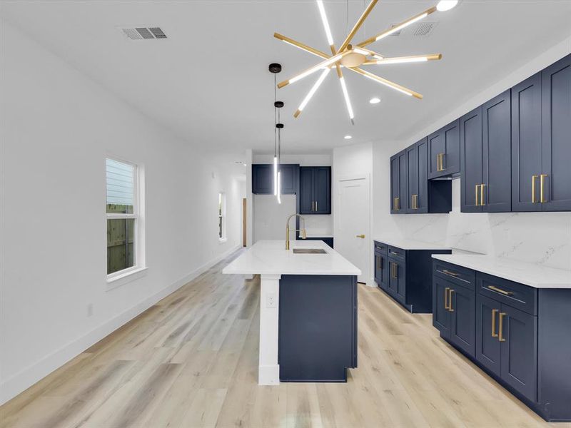 Kitchen with light hardwood / wood-style floors, sink, a kitchen island with sink, and a chandelier