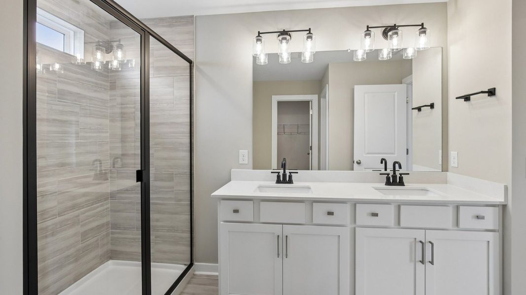 Bathroom with tile shower and glass enclosure, along with dual vanity