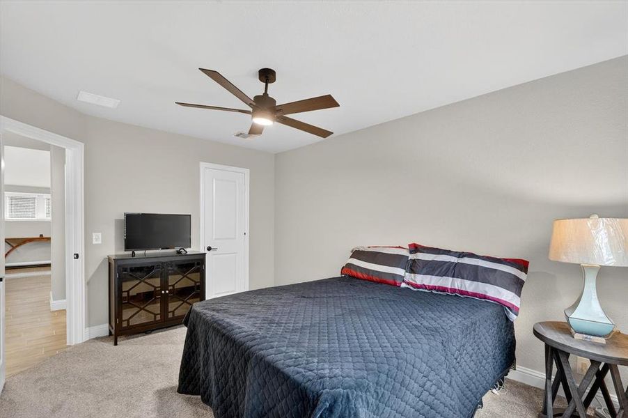 Carpeted room featuring a ceiling fan with integrated lighting, a white paneled door, and neutral wall paint Carpeted room featuring a ceiling fan with integrated lighting, a white paneled door, and neutral wall paint