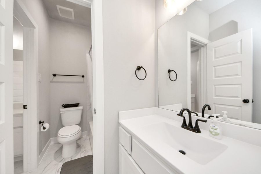 Jack-and-Jill bath with separate vanity, quartz countertops, matte-black hardware, and a private tub/toilet room.