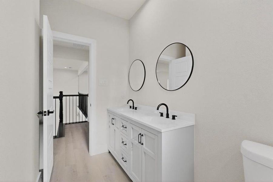 Bathroom featuring double vanity and light wood-style flooring Bathroom featuring double vanity and light wood-style flooring