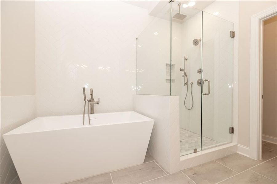 Bathroom with a freestanding bath, a stall shower, and tile patterned flooring