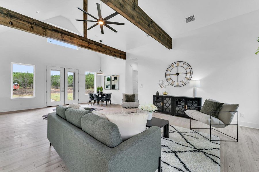 Living area with ceiling fan, light wood-type flooring, high vaulted ceiling, french doors, and beam ceiling