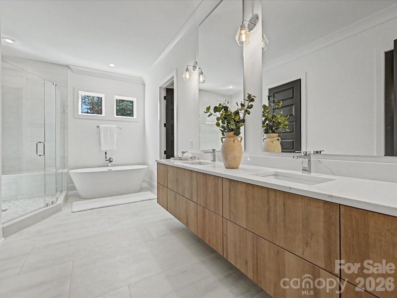 Luxurious primary bath featuring dual vanities, a freestanding soaking tub, and a walk-in glass shower, creating a spa-like retreat.