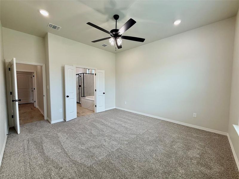 Unfurnished bedroom featuring light carpet, recessed lighting, a ceiling fan, and ensuite bath