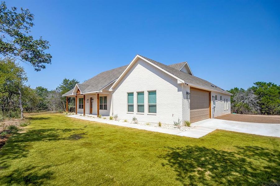 View of front facade featuring brick siding, a front yard, a porch, and concrete driveway View of front facade featuring brick siding, a front yard, a porch, and concrete driveway