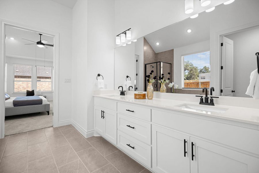 Full bath featuring ensuite bathroom, a shower stall, light tile patterned floors, double vanity, and a ceiling fan