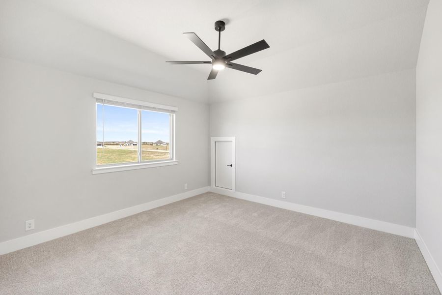 Empty bedroom with gray carpet, white walls, black ceiling fan, and a window with outdoor views Empty bedroom with gray carpet, white walls, black ceiling fan, and a window with outdoor views