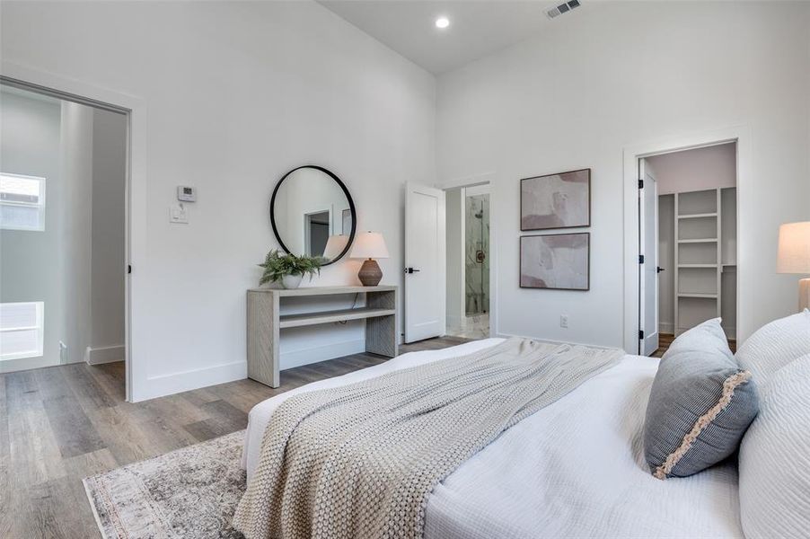 Bedroom featuring a towering ceiling, wood finished floors, a spacious closet, and recessed lighting
