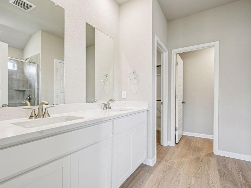 Bathroom featuring wood finished floors, double vanity, and a shower stall Bathroom featuring wood finished floors, double vanity, and a shower stall