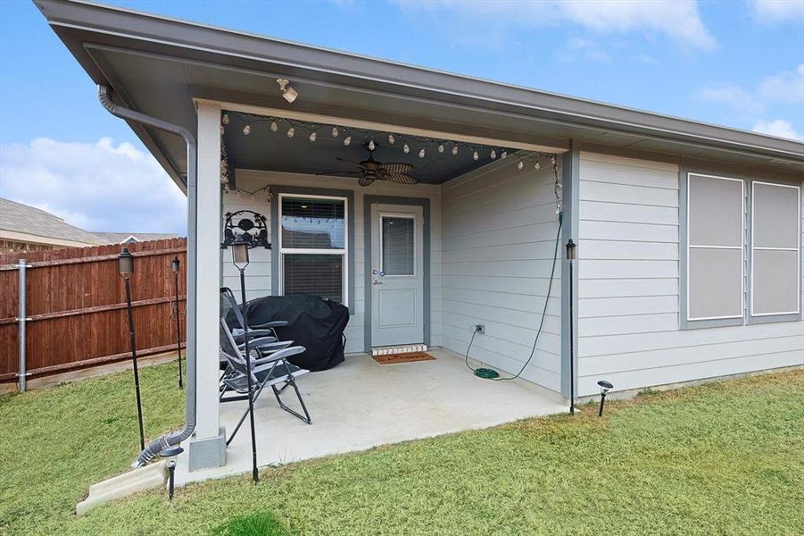 Doorway to property with a patio area, fence, a ceiling fan, and a yard