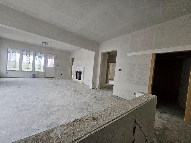 Spacious interior featuring a contemporary fireplace with a white mantel, multiple windows, and an exterior door Spacious interior featuring a contemporary fireplace with a white mantel, multiple windows, and an exterior door