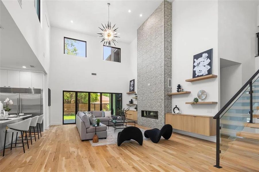 Expansive double-height living area featuring a floor-to-ceiling stone-clad fireplace and light wood-finish flooring Expansive double-height living area featuring a floor-to-ceiling stone-clad fireplace and light wood-finish flooring