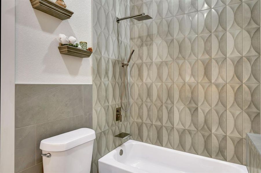 Bathtub and shower combination featuring geometric wall tile with a rain shower head and handheld sprayer Bathtub and shower combination featuring geometric wall tile with a rain shower head and handheld sprayer