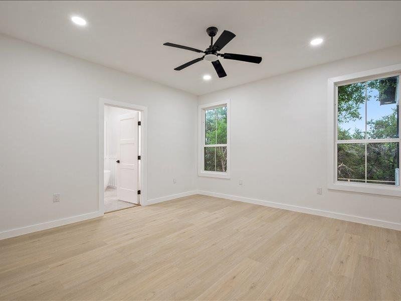 The room features light wood flooring, white walls, and a black ceiling fan