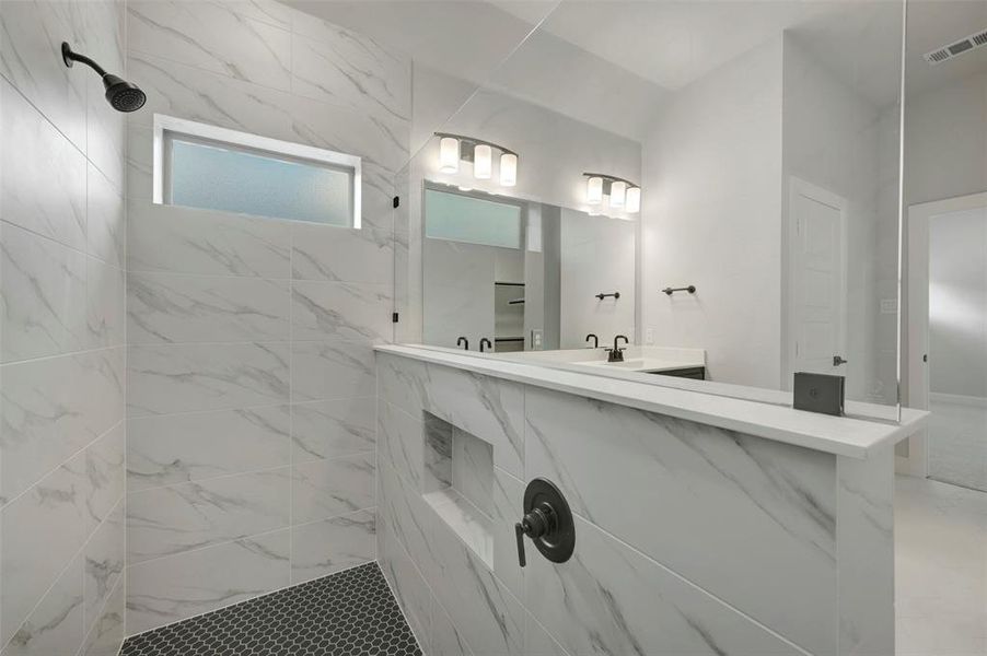 Bathroom featuring a marble finish shower and vanity