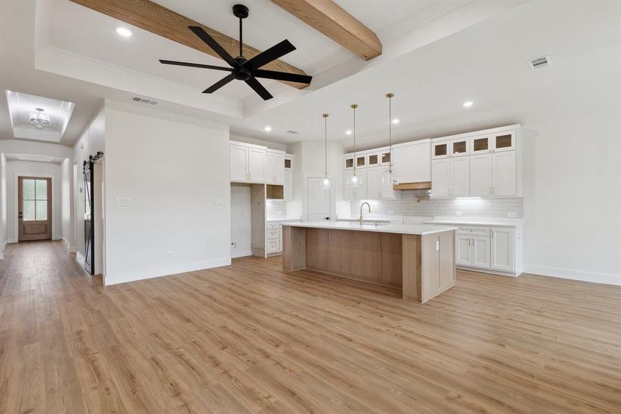 Kitchen with backsplash, a sink, beam ceiling, a barn door, and visible vents