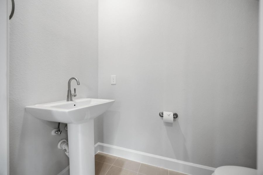 Nestled under the stairs, this powder room features a timeless pedestal sink, combining convenience and classic style.