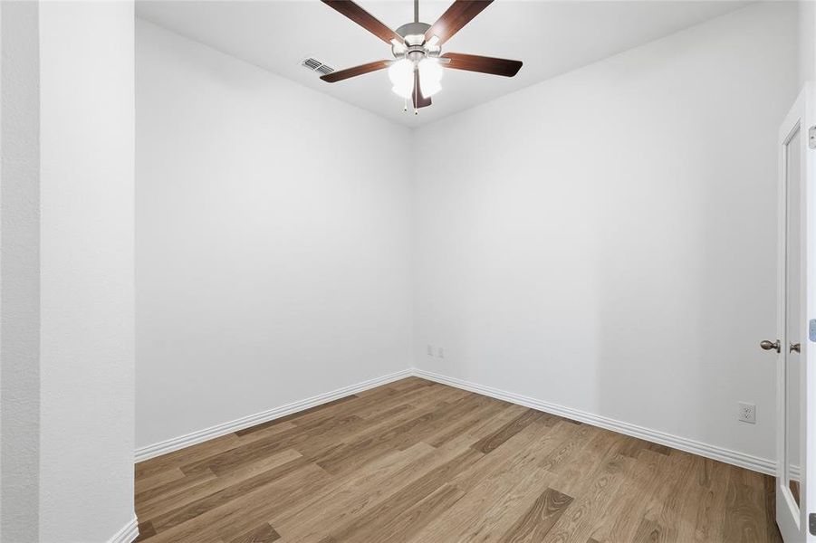 Room featuring wood-finish flooring, white baseboards, and a ceiling fan with integrated lighting