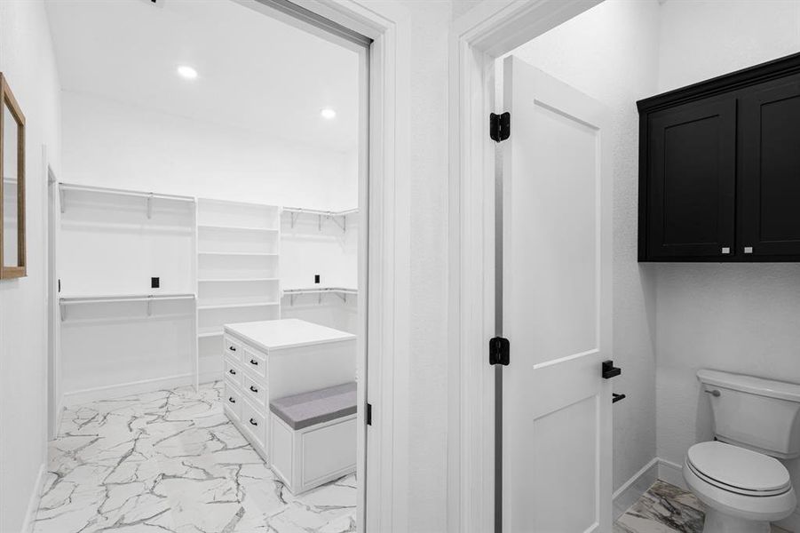 Bathroom featuring light marble finish flooring, a spacious closet, and recessed lighting