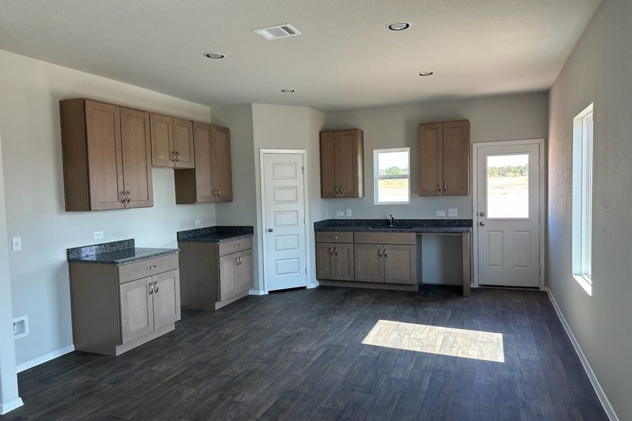 Image of home kitchen with light brown cabinets, wood-look floors, and window on wall, rear door, and over sink Image of home kitchen with light brown cabinets, wood-look floors, and window on wall, rear door, and over sink