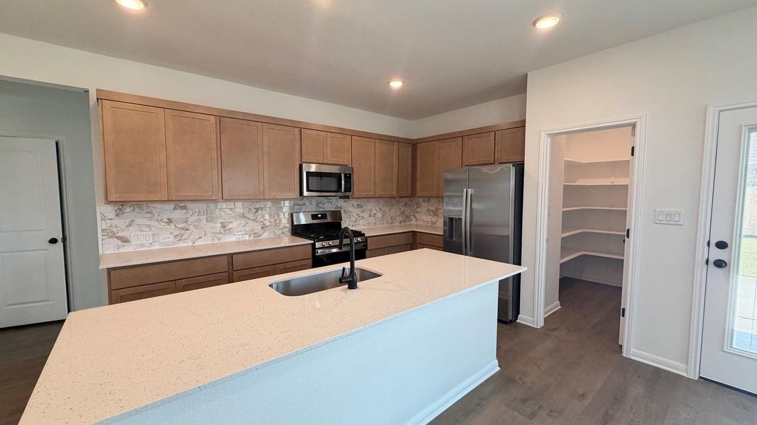 A well-appointed kitchen features a large island, stainless steel appliances, and convenient walk-in pantry. A well-appointed kitchen features a large island, stainless steel appliances, and convenient walk-in pantry.
