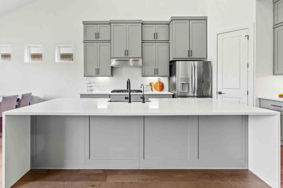 Kitchen featuring a substantial island with countertop, gray shaker cabinetry, stainless steel appliances, a gas cooktop, and a matte black faucet
