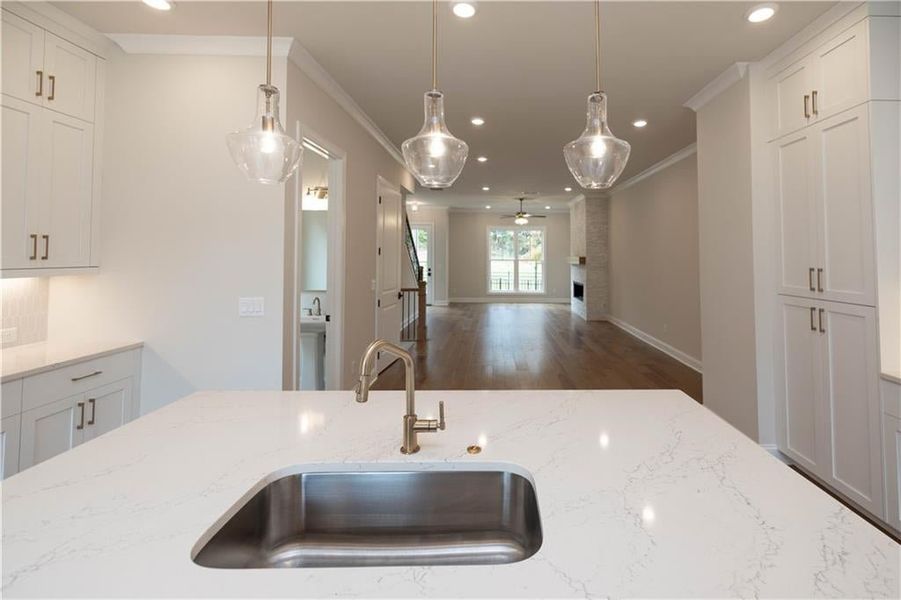 Kitchen featuring crown molding, sink, light stone counters, and decorative light fixtures