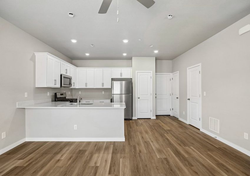 The kitchen has stainless steel appliances and plank flooring.