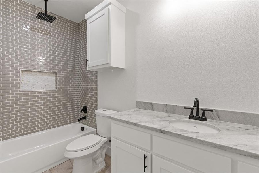 Full bathroom featuring vanity, toilet, and tiled shower / bath combo