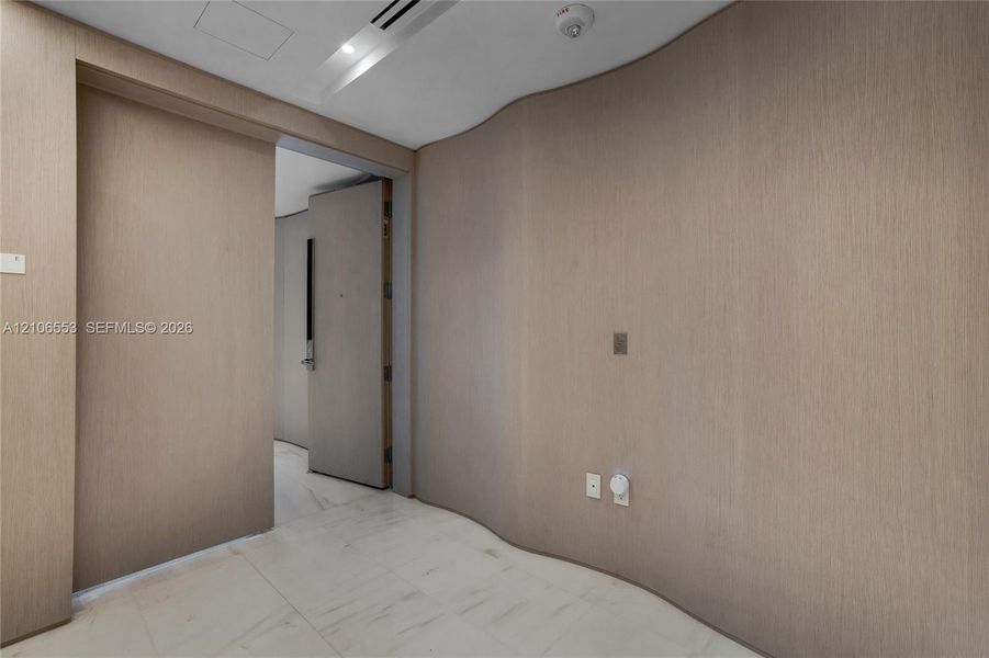 Curved wood-finish wall paneling, full-height sliding door, and stone-finish flooring