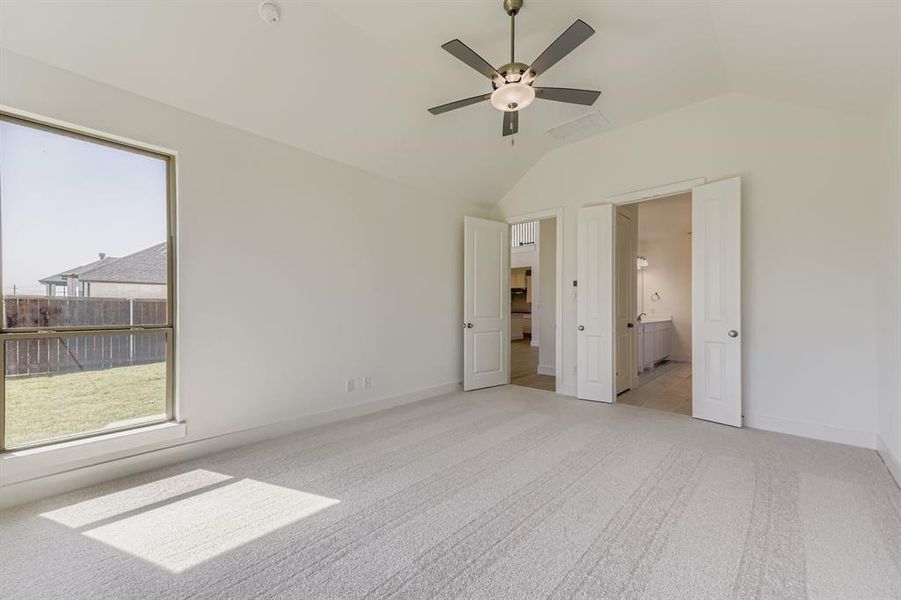 Unfurnished bedroom with light carpet, vaulted ceiling, ceiling fan, and connected bathroom Unfurnished bedroom with light carpet, vaulted ceiling, ceiling fan, and connected bathroom