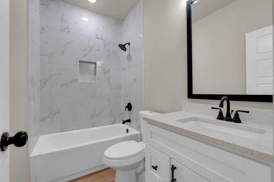 Full bathroom featuring hardwood / wood-style floors, tiled shower / bath, toilet, and vanity